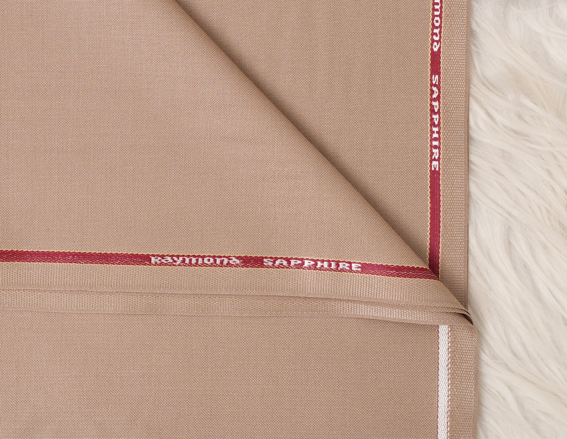 Close-up of beige fabric with 'Raymond Sapphire' branding.